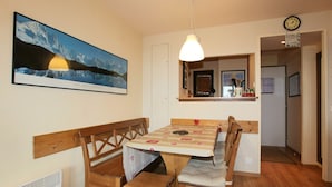 A dining area with a wooden table and benches, a pendant light, a framed picture on the wall, and a clock. - 3-room apartment, sleeps 6 in Avoriaz (Avoriaz)