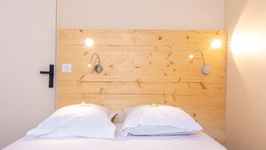 A bedroom with a wooden headboard, two bedside lamps, and a white bed with pillows.