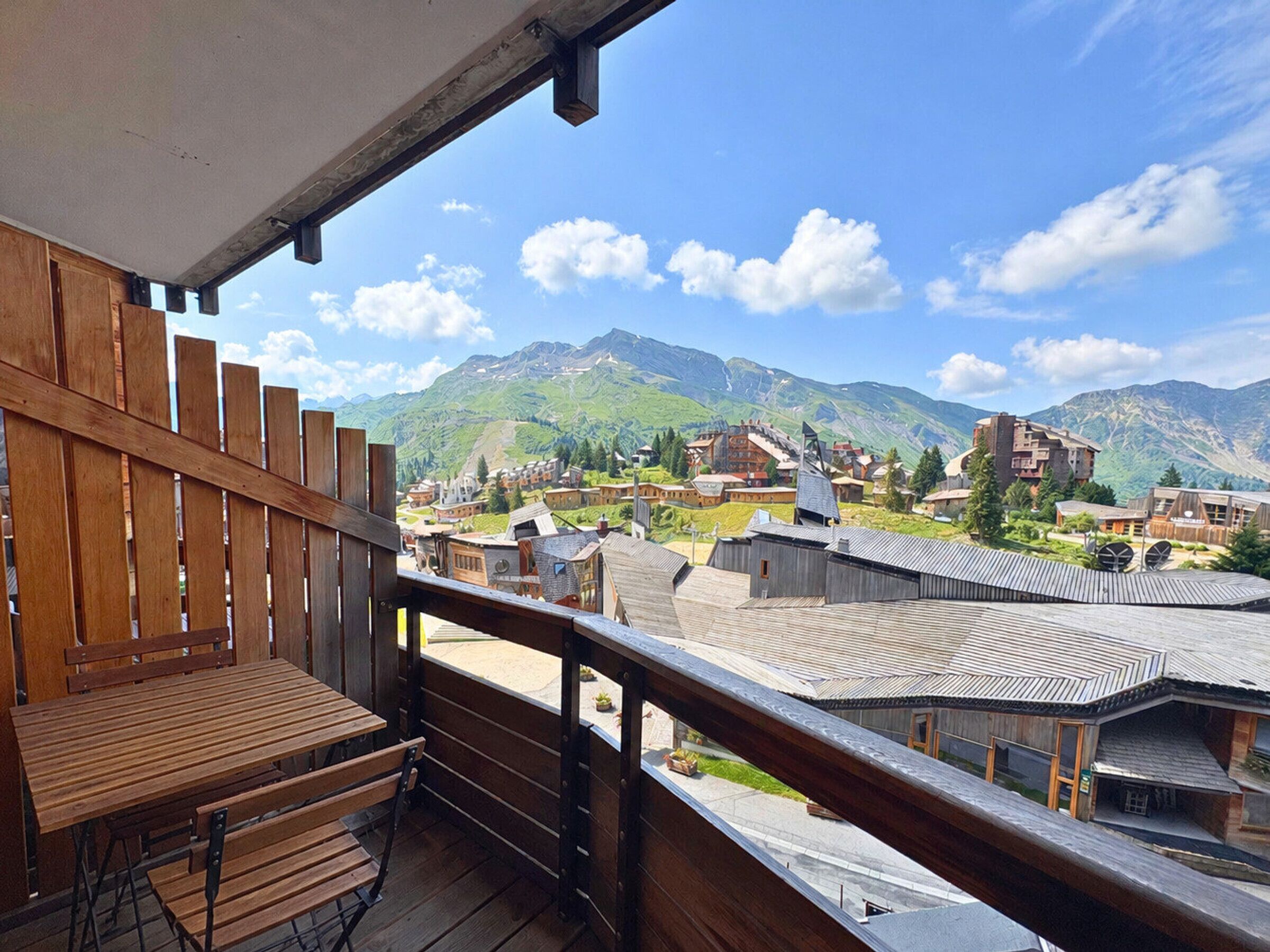 A wooden balcony with a view of a mountain village and buildings.