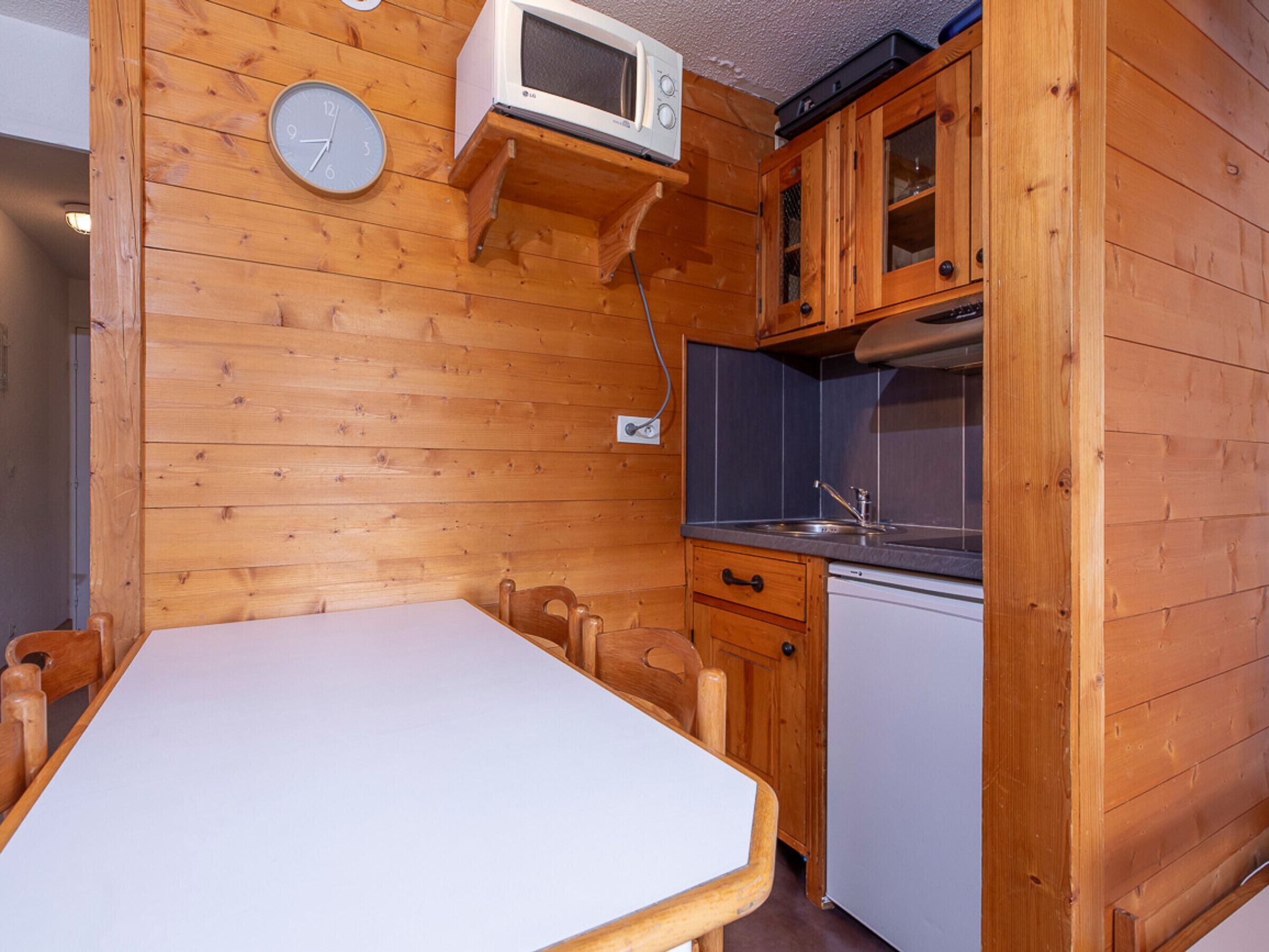 Una cocina pequeña con paredes de madera, una mesa blanca y un microondas.