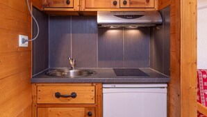 Cocina compacta con armarios de madera, un lavamanos de acero inoxidable y un lavavajillas integrado.