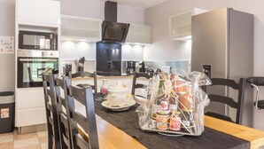A modern kitchen with a microwave, oven, and stove. There is a dining table with chairs and a small decorative item on the table. - Peaceful country house with wifi and pets allowed, near cultural sites (Villedieu-les-Poêles)