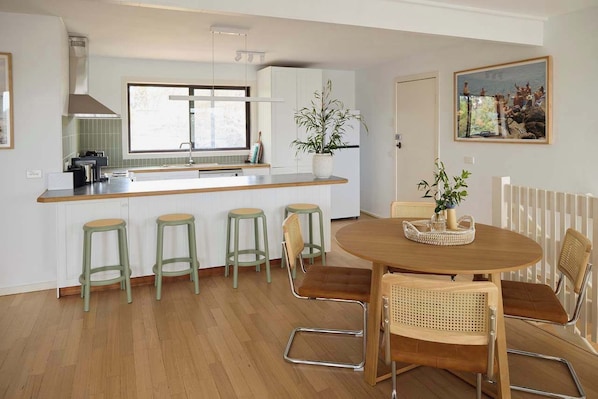 Una cocina moderna con una isla central, taburetes de bar y una mesa de comedor con sillas.