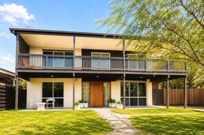 A two-story house with a balcony, a covered patio, and a well-maintained lawn.