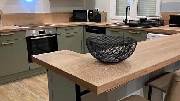 A modern kitchen with a wooden countertop, a built-in microwave, and a sink.