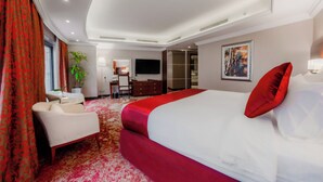 Une chambre d’hôtel avec un grand lit, un bureau, une chaise, une télévision et une plante.