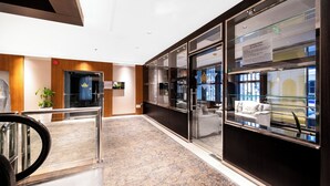 Un hall d’hôtel moderne avec un sol en marbre, un comptoir d’accueil et une vitrine en verre.