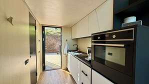 Eine moderne Küche mit Einbauofen und Mikrowelle, Holzboden und Blick ins Freie.