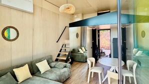 Ein modernes Wohnzimmer mit einer Couch, einem Esstisch mit Stühlen, einer Treppe und einem großen Fenster.