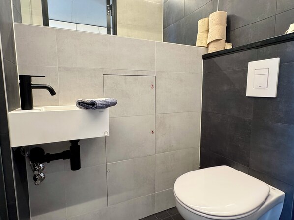 A modern bathroom with a white sink, black faucet, and a toilet.