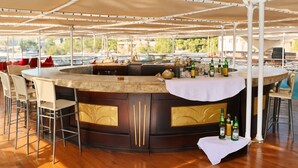 Eine Bar mit einer gebogenen Theke, Barhocker und Bierflaschen.