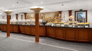 Ein Buffetbereich mit mehreren Speiseausgaben, einer großen Zierkolonne und einem Wandgemälde.