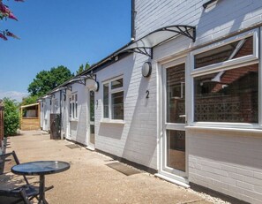 A row of white buildings with numbered windows, outdoor seating, and a logo for Ashdene House.