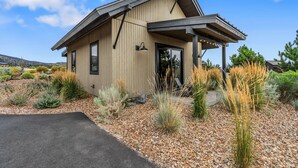 Een modern huis met een houten gevel, een overdekte veranda en een grindpad.