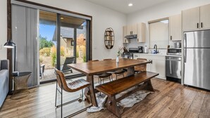 Een moderne keuken met een houten eettafel, inbouwapparatuur en een schuifdeur naar een terras.