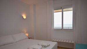 Ett hotellrum med en säng, ett nattduksbord, ett fönster med utsikt och ett element.
