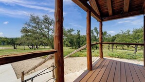 Eine Holzterrasse mit Blick auf eine Wiese und Bäume.