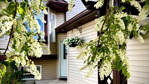 A two-story house with a front porch and a small garden area. - Harper House-Home away from home in Lethbridge (Lethbridge)