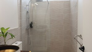 Een kleine badkamer met douche, toilet en wastafel.