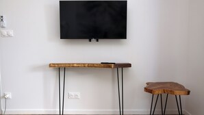 Een kamer met een wandgemonteerde flatscreen-tv, een houten console en een klein krukje.