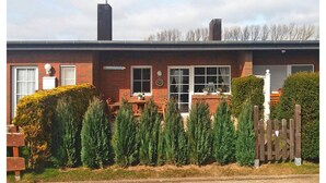 A brick house with a chimney, a front door, and a small porch with a table and chairs. - Reihenhaus Land and Sea in Busum (Westerdeichstrich)