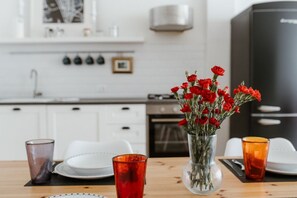 Ein Esstisch mit einer Vase roter Blumen, Tellern und Gläsern.