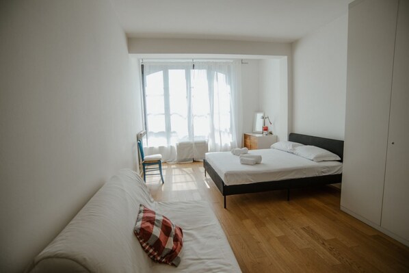 A bedroom with a bed, a chair, a nightstand, and a wardrobe.