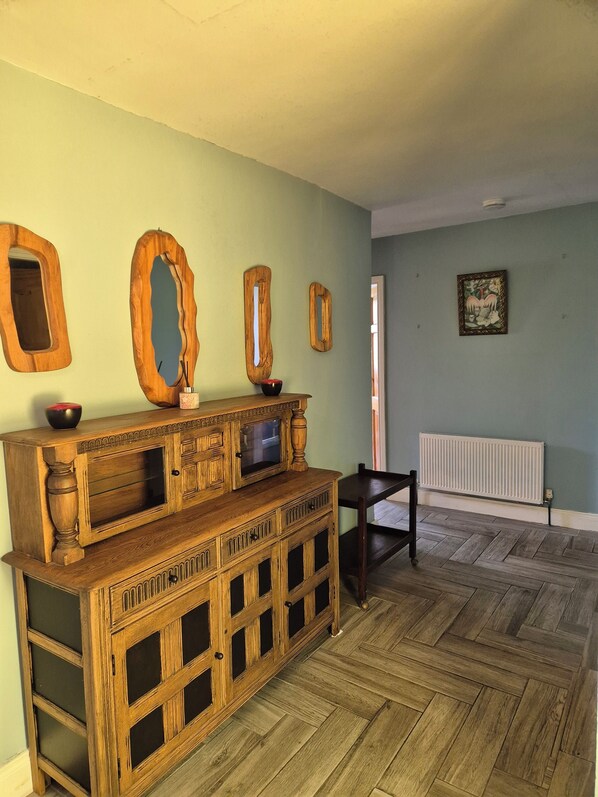 A room with a wooden cabinet, a radiator, and a herringbone-patterned floor.