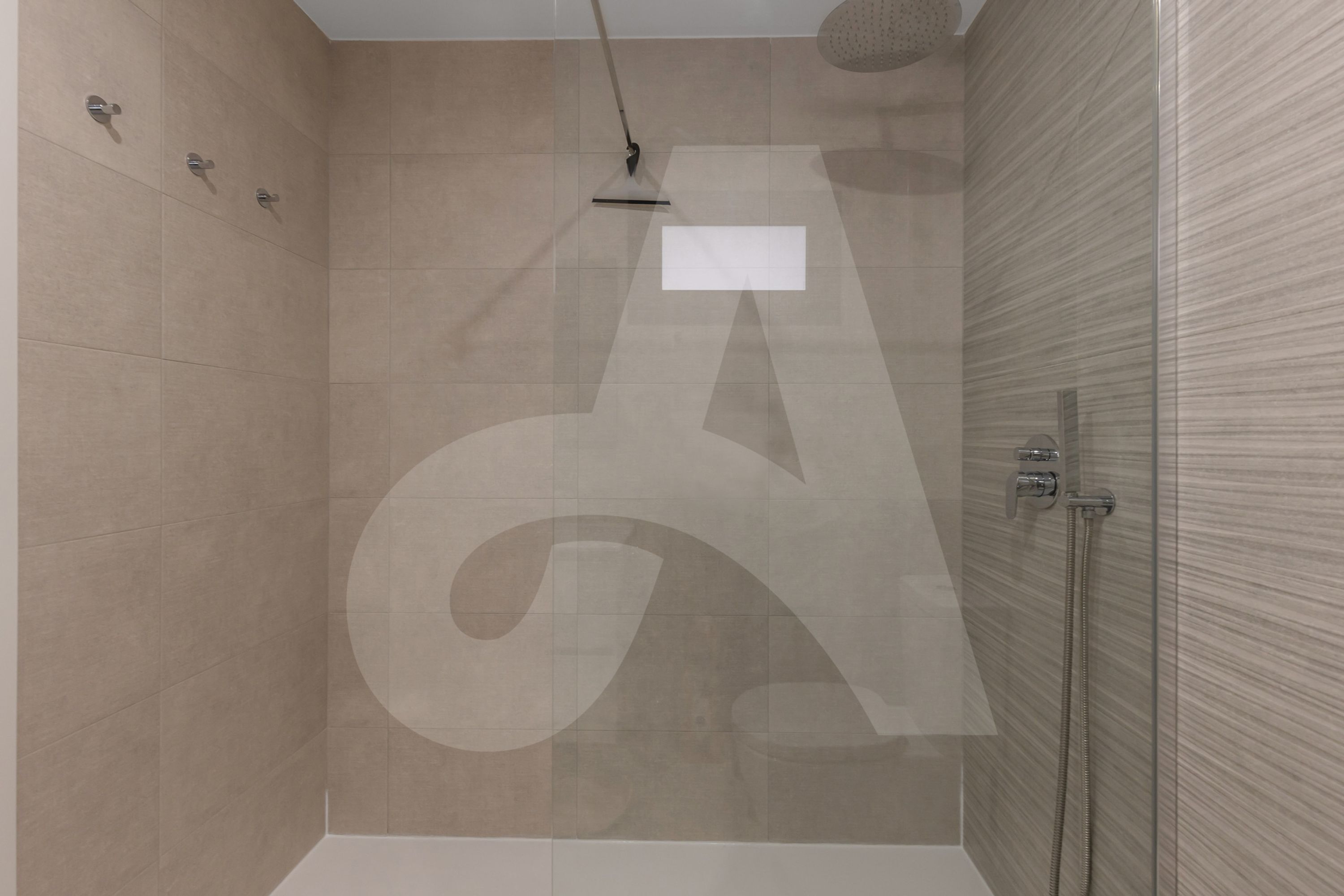 A modern shower area with a glass door, a handheld showerhead, and a wall-mounted control panel.