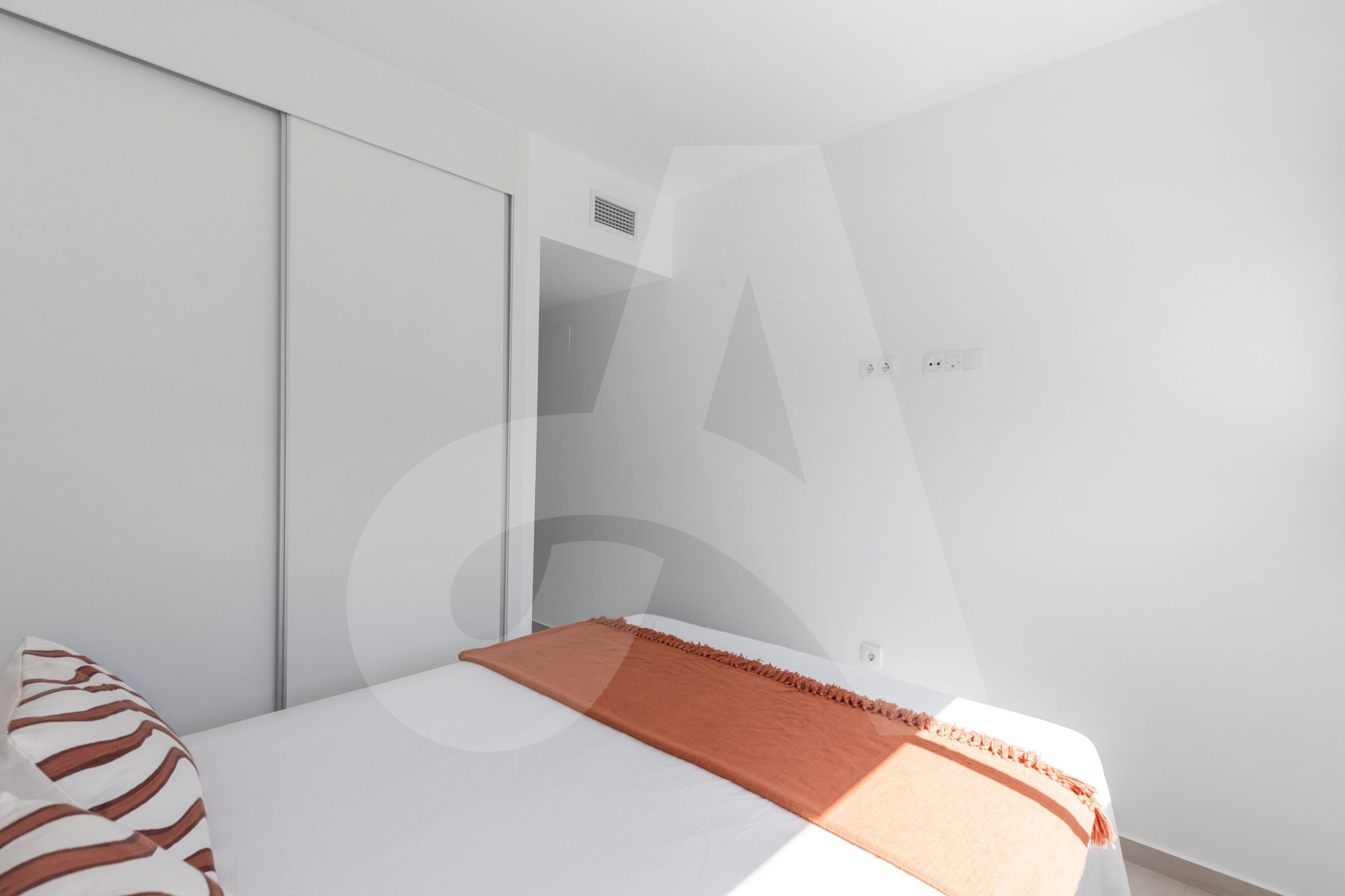 A bedroom with a bed, a wardrobe, and a door.