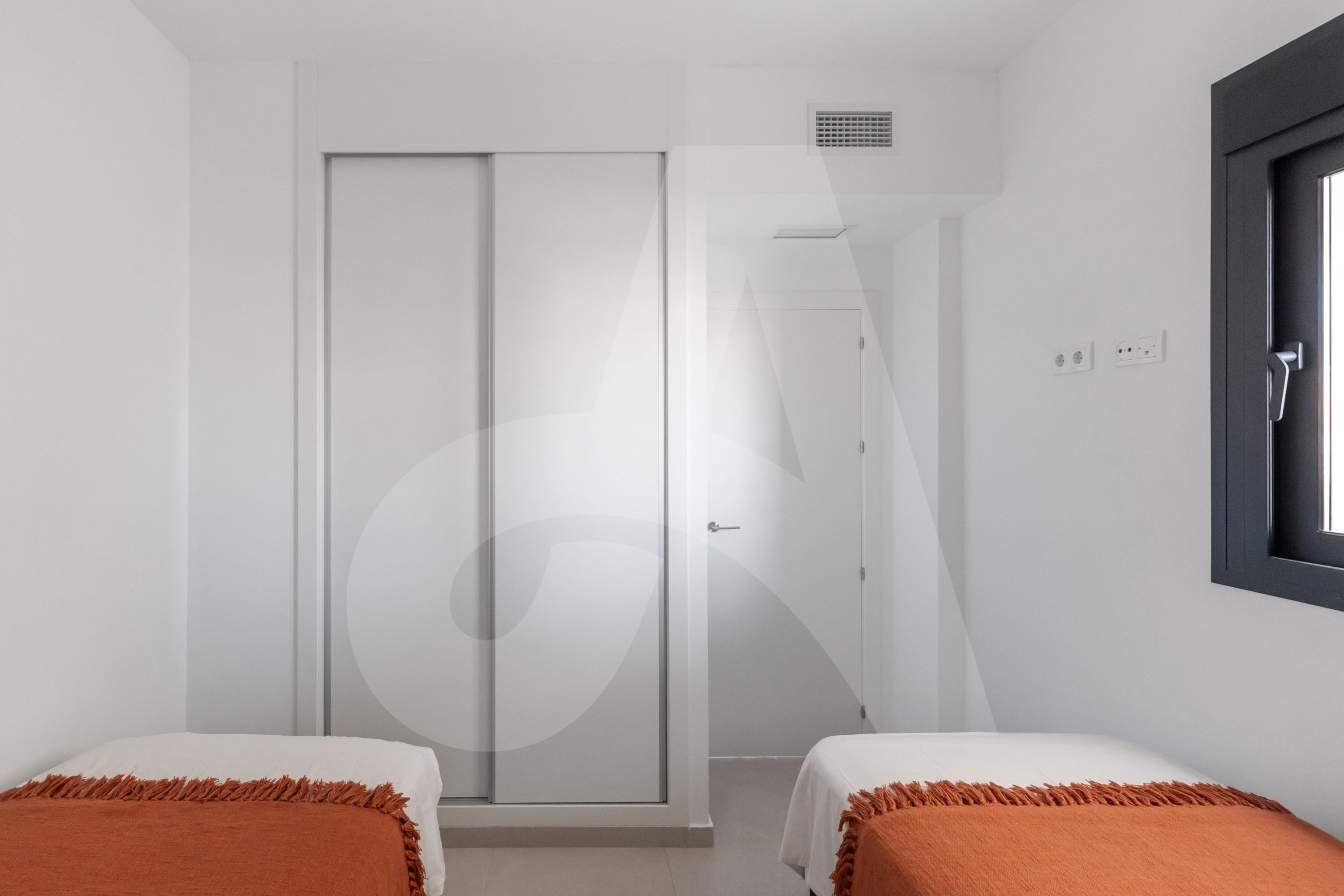 A bedroom with two beds, a wardrobe, a window, and a door.