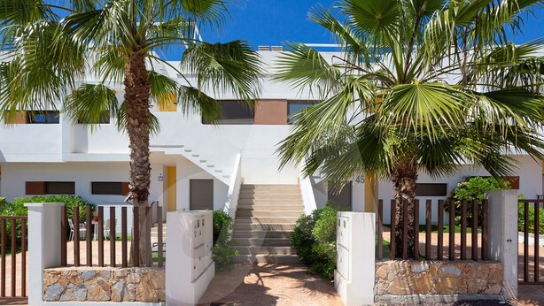 A building entrance with a staircase leading to the upper floors, surrounded by palm trees and a gated area. - Casa de Lipa in Orihuela Costa (Orihuela)