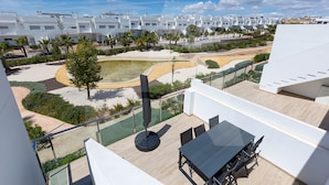 A rooftop terrace with a dining table and chairs, surrounded by a landscaped garden with palm trees and a small pond. - Casa de Lipa in Orihuela Costa (Orihuela)