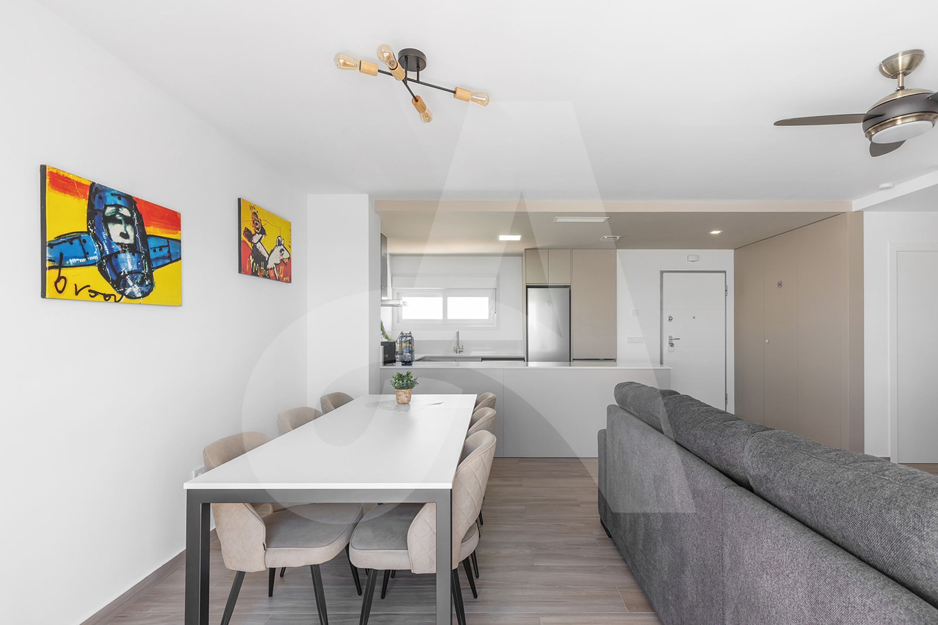 A modern kitchen with a central island, white cabinetry, and a built-in oven.