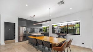 Une cuisine moderne dotée d’un îlot central, de meubles de rangement aux couleurs sombres et d’une grande fenêtre offrant une vue sur l’extérieur.