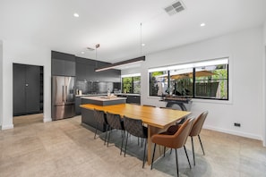 Una cocina moderna con una isla central, armarios oscuros y un amplio ventanal con vistas al exterior.