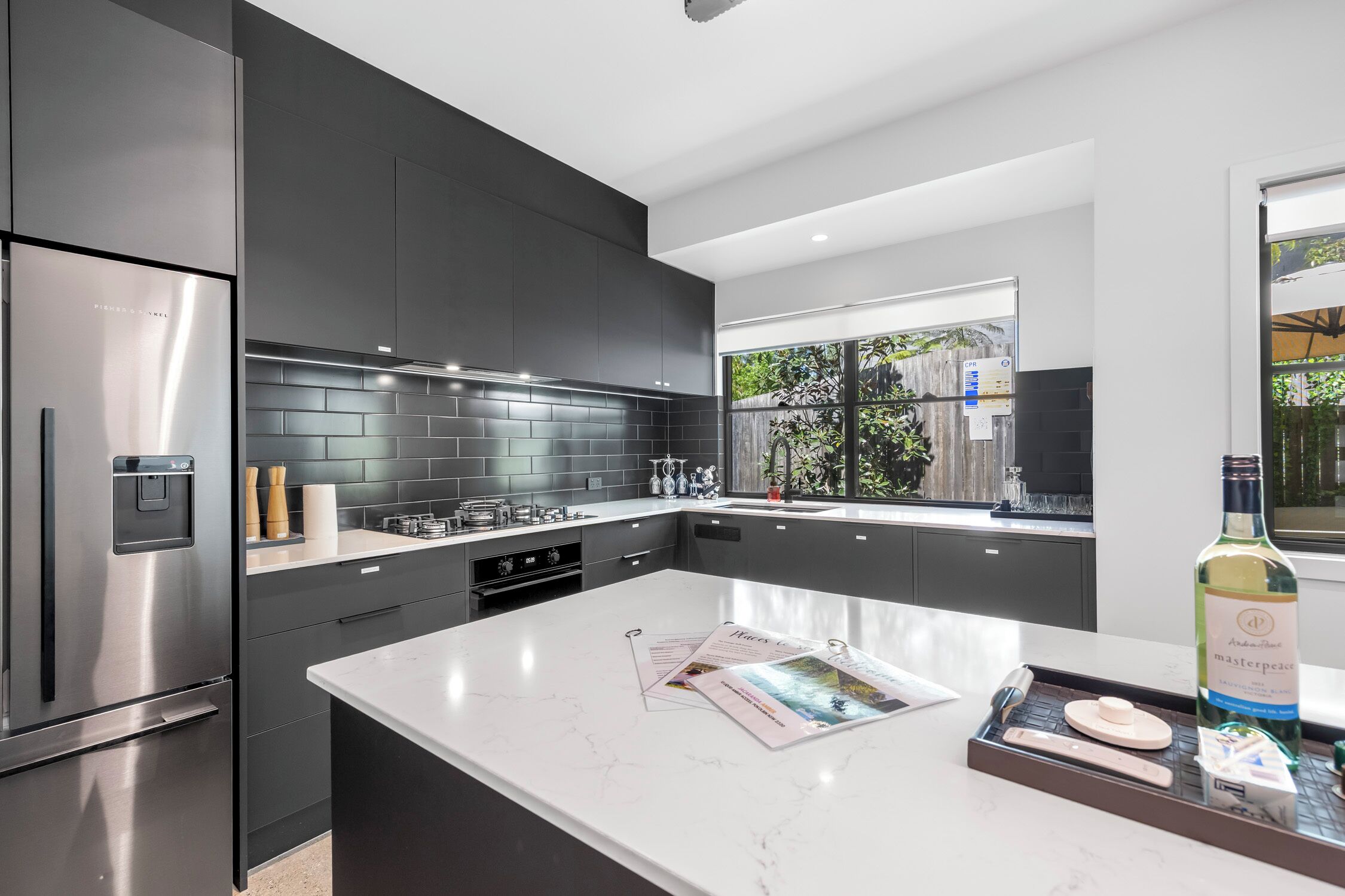 Una cocina moderna con armarios oscuros, un refrigerador de acero inoxidable y una encimera de mármol.