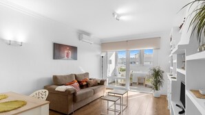 Un salon moderne avec un canapé, une table à manger et un balcon offrant une vue agréable.