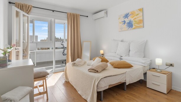 Une chambre à coucher avec un lit, des tables de chevet, un bureau et une fenêtre avec des rideaux.