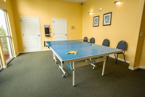 Et ping pong-bord i et rum med gule vægge, to hvide døre og et vindue.