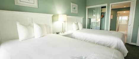 Une chambre d’hôtel avec deux lits, une table de chevet, une lampe et un miroir.