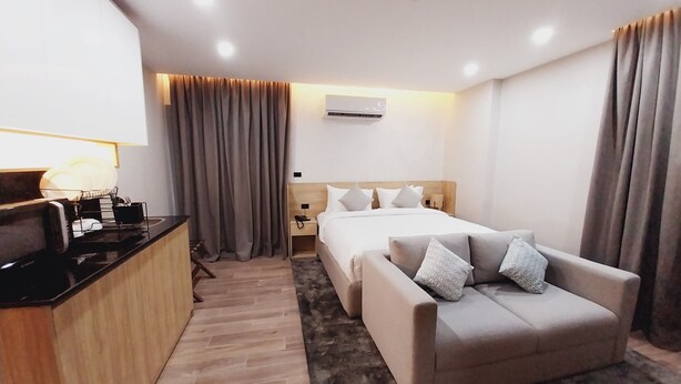 Une chambre d’hôtel équipée d’un lit, d’un canapé, d’un bureau avec une lampe et d’un appareil de climatisation.