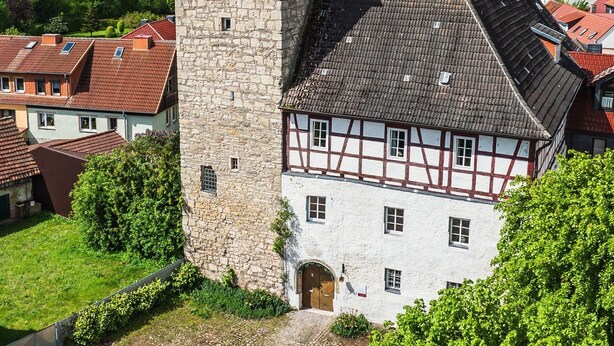 A historic stone tower and a traditional half-timbered building with a cobblestone courtyard. - Vacation in the castle up to 15 pers. Apartment: Burggraf & Himmelsleiter (Großbodungen)