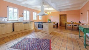 A spacious kitchen with wooden cabinets, a central island, and a dining area with a wooden table and chairs. - Vacation in the castle up to 15 pers. Apartment: Burggraf & Himmelsleiter (Großbodungen)