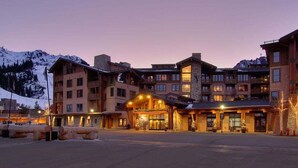 A multi-story hotel with a central lobby, multiple balconies, and a mountainous backdrop.