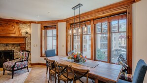 A cozy dining area with a wooden table, chairs, and a stone fireplace.