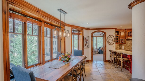 A spacious dining area with a long wooden table, multiple chairs, and large windows providing natural light.