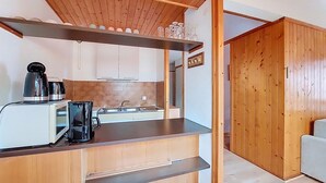 A compact kitchen with wooden cabinets, a built-in oven, and a coffee maker.
