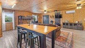 Un interior rústico de madera con zona de comedor, asientos de bar y televisor.