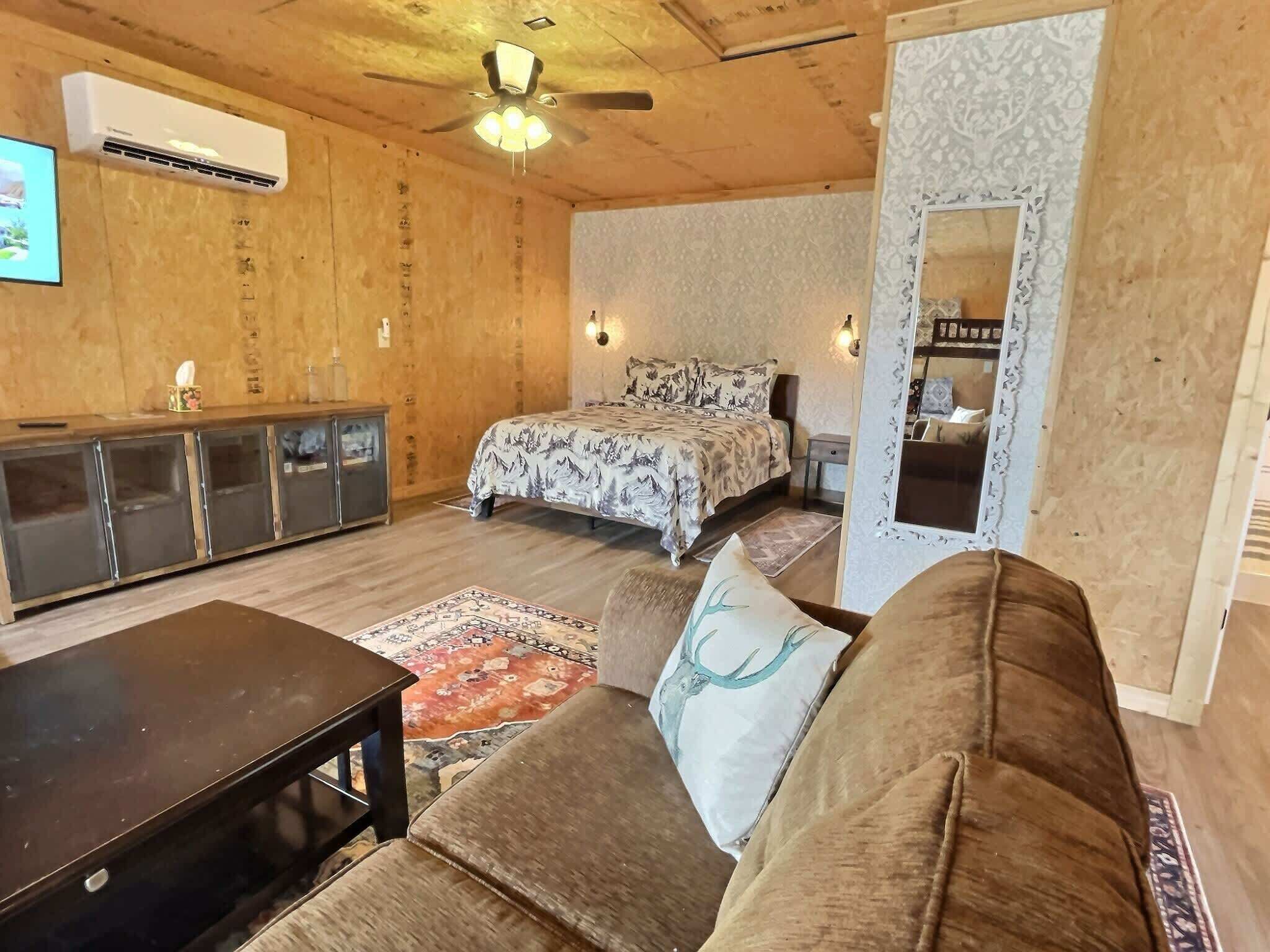Une pièce comprenant un lit, un canapé, une télévision, une armoire et un ventilateur de plafond.